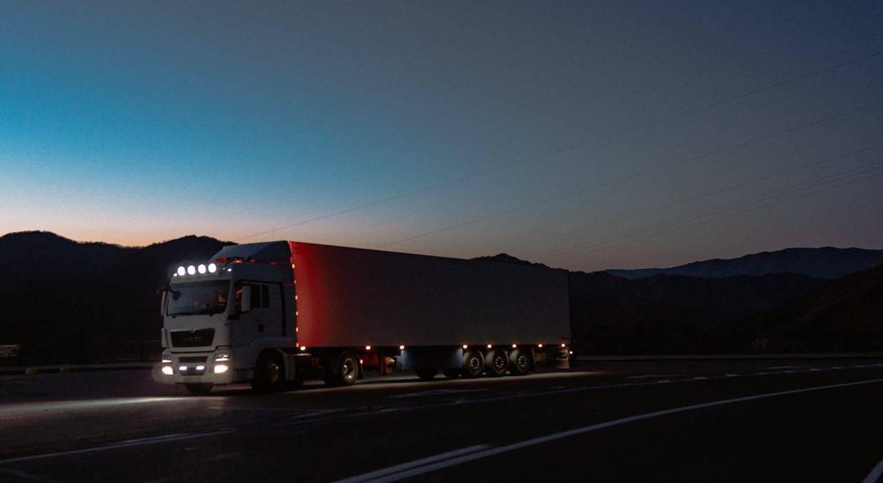 A semi-truck on a long highway under dark skies