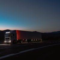 A semi-truck on a long highway under dark skies