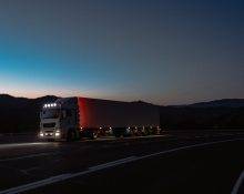 A semi-truck on a long highway under dark skies
