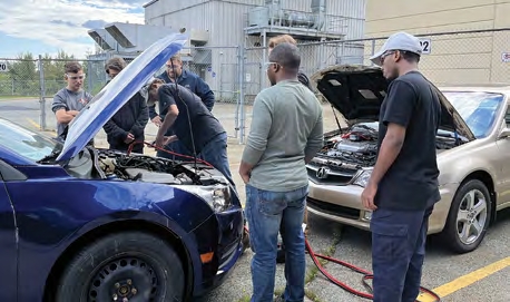 Cohort of 6 individuals jump-starting a dead vehicle together